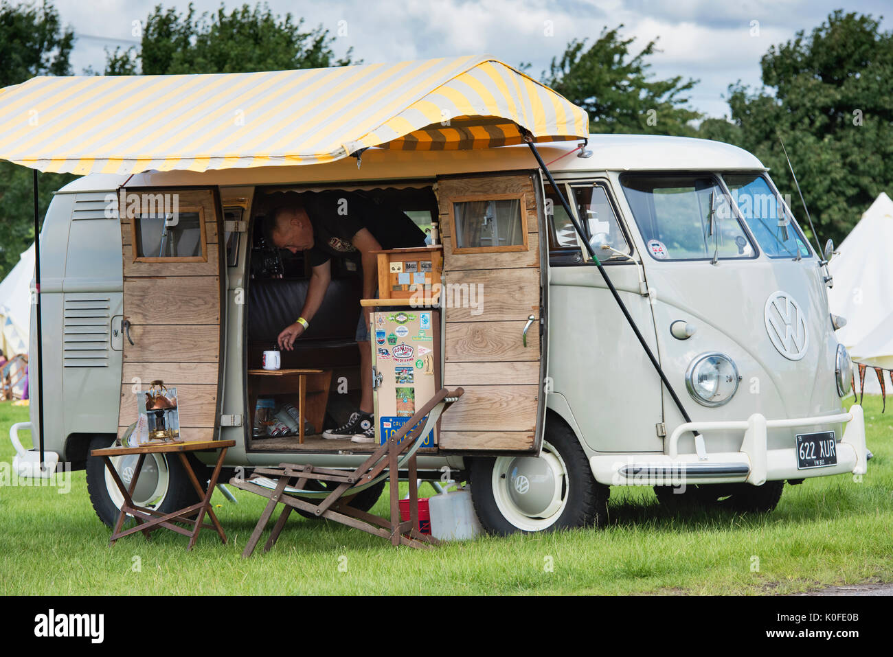 Mann, eine Tasse Tee in einen 1958 VW split screen Wohnmobil an einem Vintage Retro Festival. Großbritannien Stockfoto