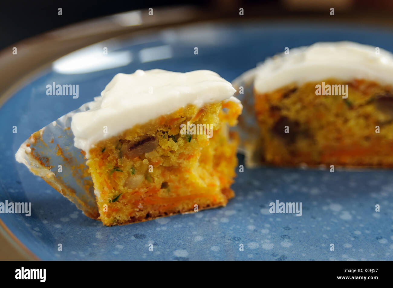 Zucchini und Karotten Cupcakes mit Philadelphia Käse Creme auf blauen Platte auf der schwarzen Oberfläche Stockfoto