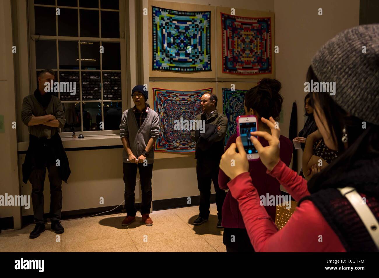 Ein Student macht ein Bild von einem anderen Studenten während der Eröffnung der Kunstausstellung "Unravel the Code," eine Zusammenarbeit zwischen Studenten des Maryland Institute College of Art und der Johns Hopkins University, In der Milton S. Eisenhower Library auf dem Homewood Campus der Johns Hopkins University in Baltimore, Maryland, 2013. Mit Freundlicher Genehmigung Von Eric Chen. Stockfoto