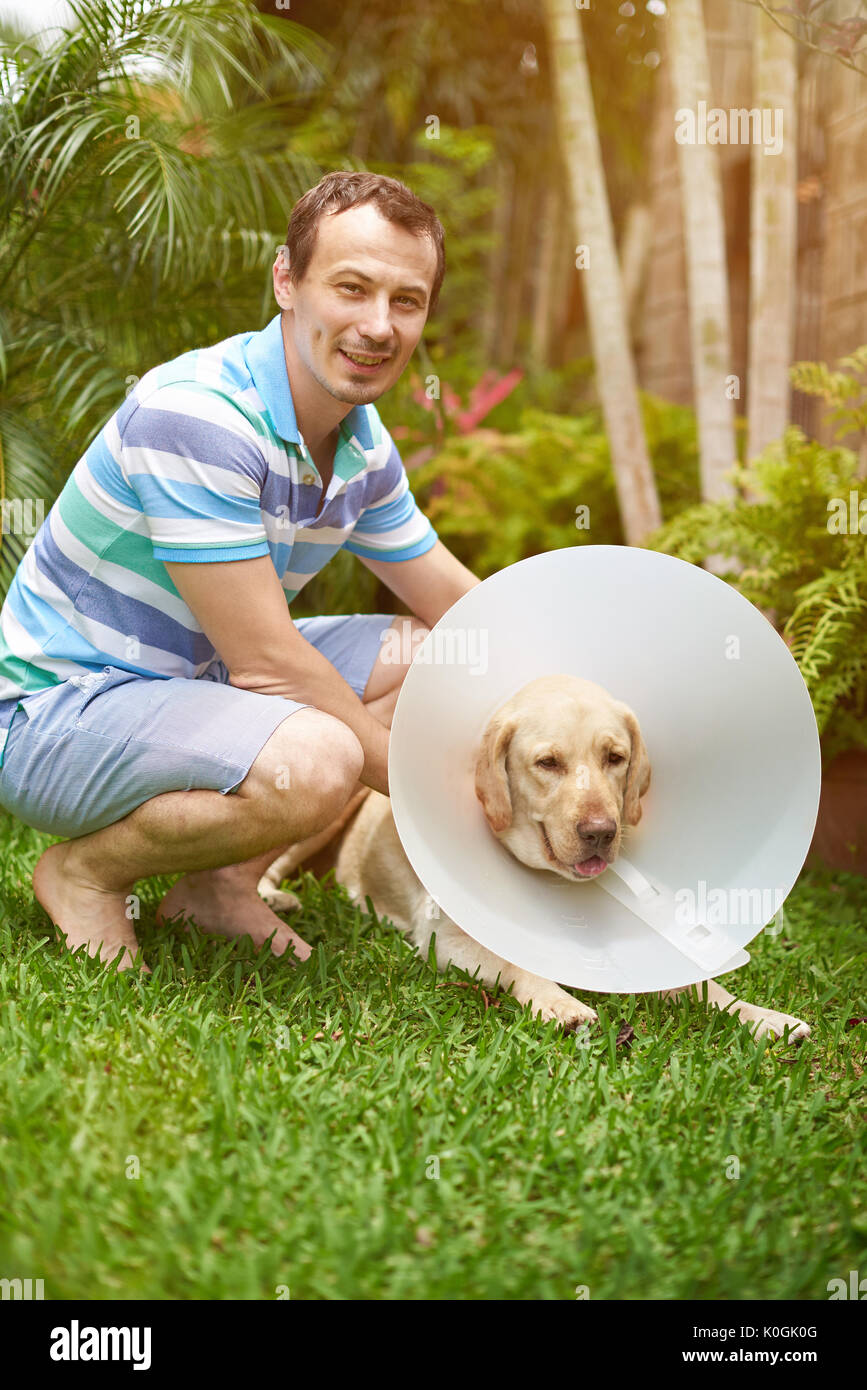 Junger Mann mit Labrador Hund in Kegel Kragen Stockfoto