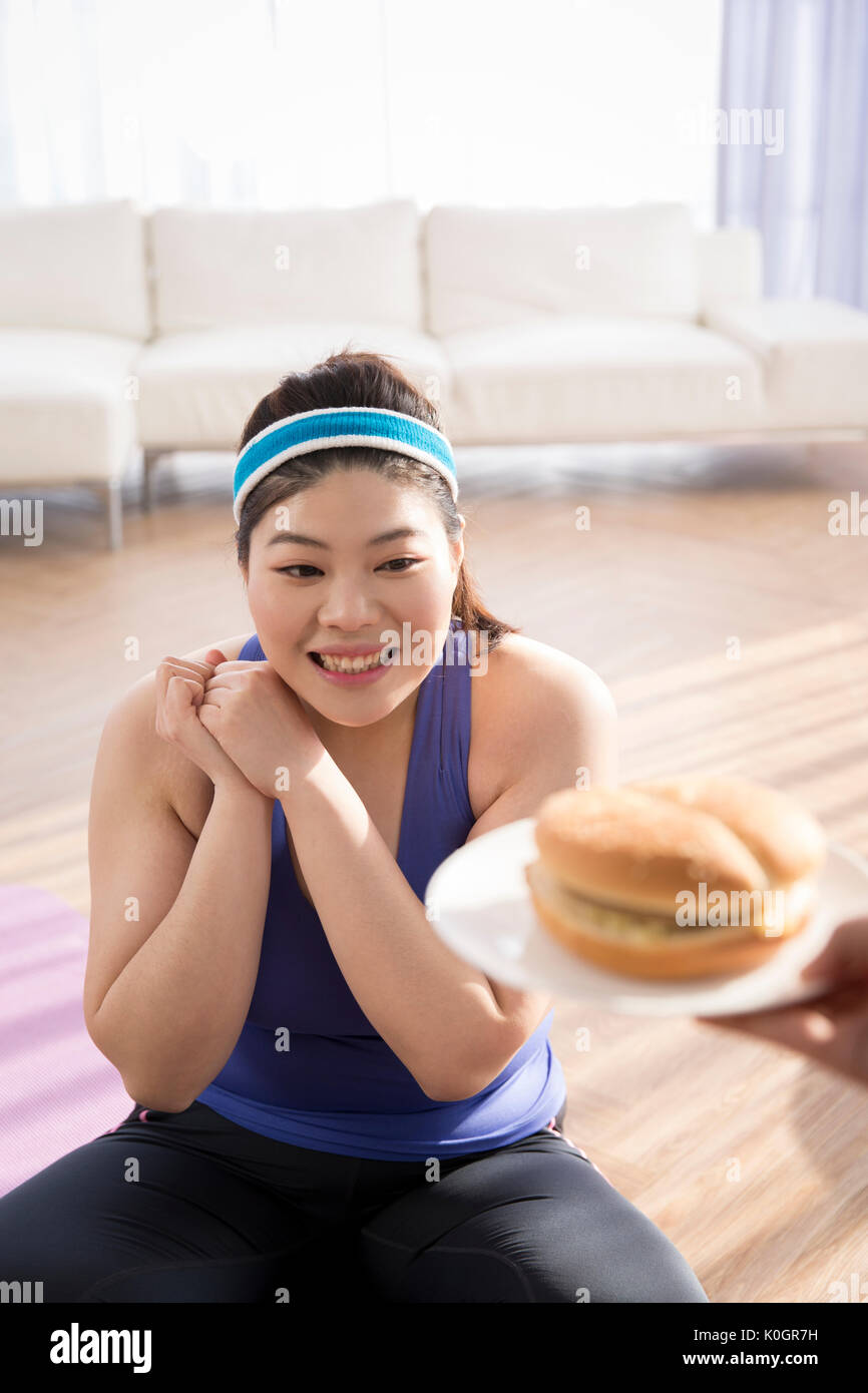 Junge lächelnde fette Frau versucht schnell zu Essen - Essen Stockfoto