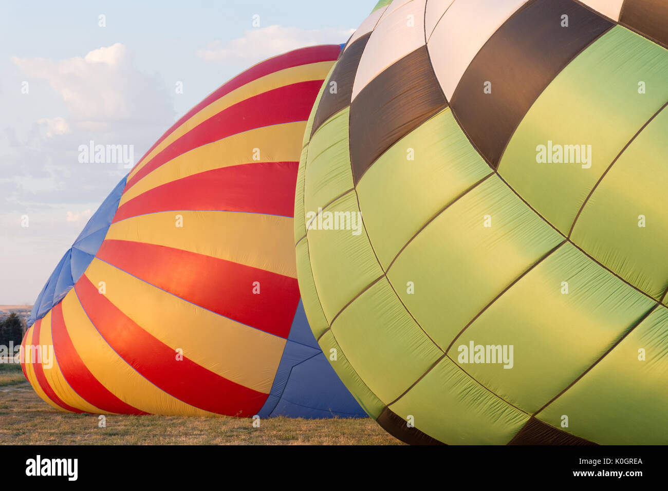 Zwei bunte Luftballons, bei Sonnenaufgang aufgeblasen. Das Licht auf dem Rot, Blau und Gold Ballon und Weiß, Grün und Schwarz Luftballon golden ist. Stockfoto