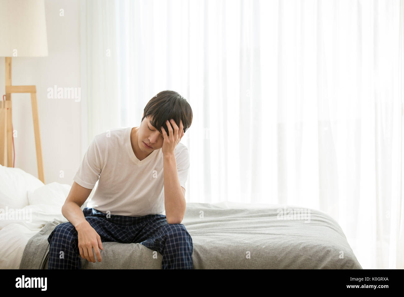 Single Mann mit Kopfschmerzen sitzen auf dem Bett Stockfoto