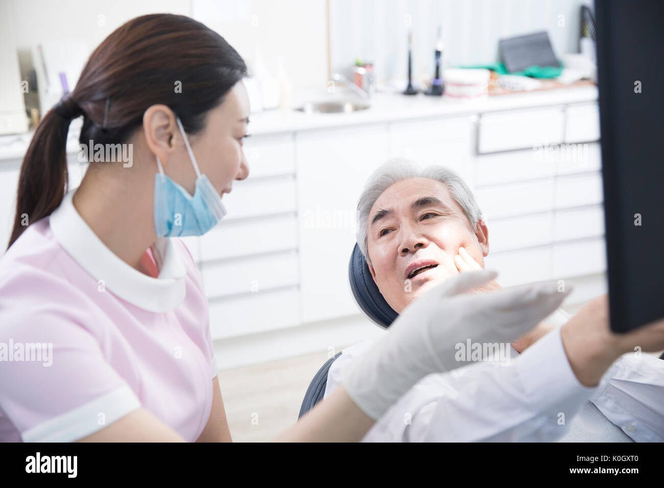 Portrait von lächelnden Zahnarzthelfer und einem lächelnden älteren männlichen Patienten Stockfoto