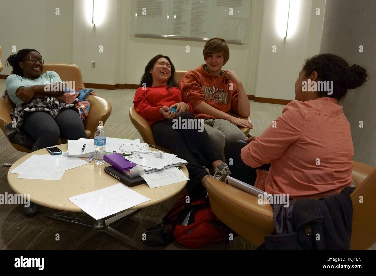 Vier Studenten in drei Stühle in der Brody Learning Commons sitzen, durch Studium Materialien umgeben, lachen Mimik, 2016. Mit freundlicher Genehmigung von Eric Chen. Stockfoto