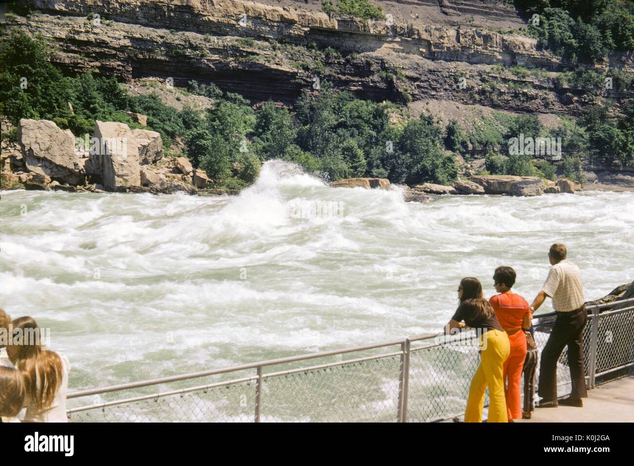 Touristen gegen einen Zaun am Rand der Gehweg, der entlang ein schweres Wildwasser auf einem schnell fließenden Fluss gebaut wurde Lean, die felsige Küste kann im Hintergrund, 1960 gesehen werden. Stockfoto