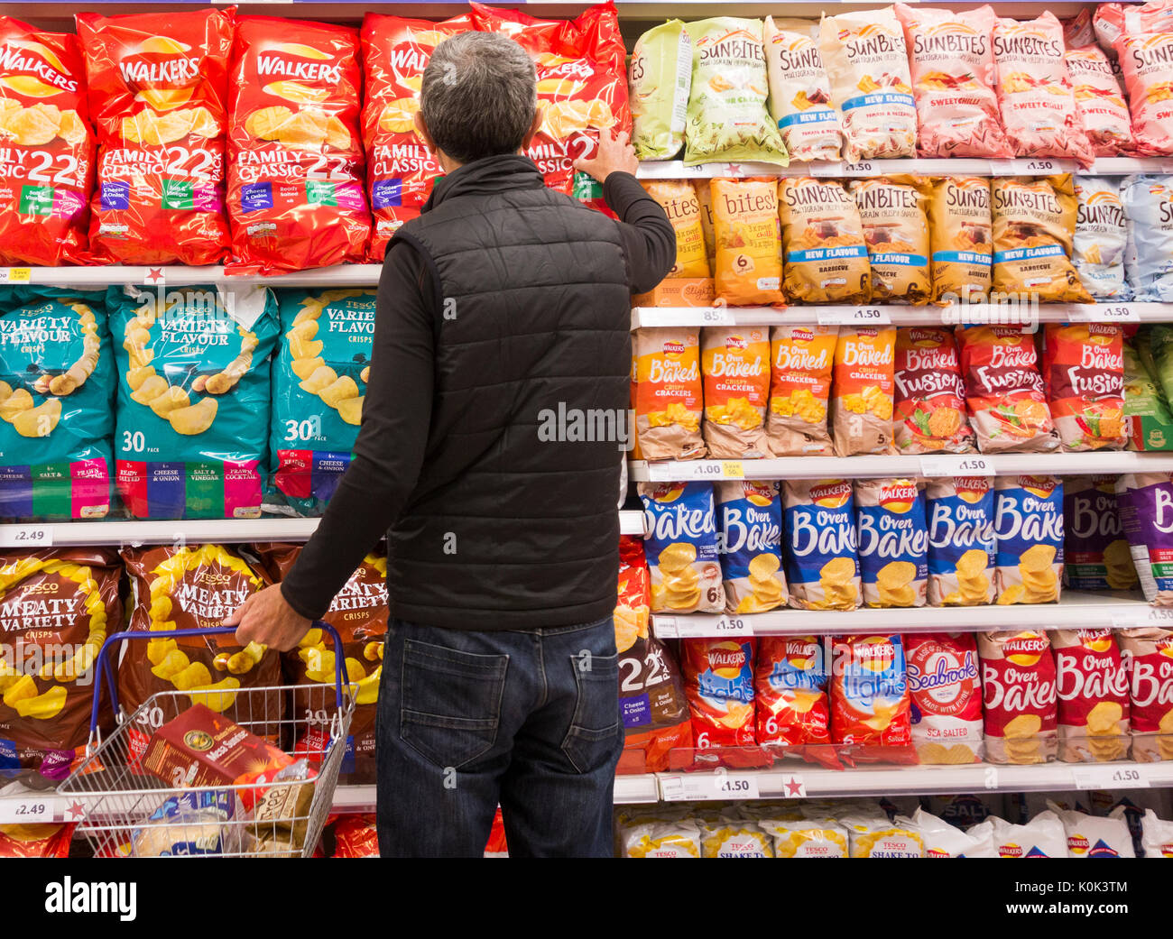 Mann kaufen Großes pack Chips in Tesco Supermarkt. Großbritannien Stockfoto