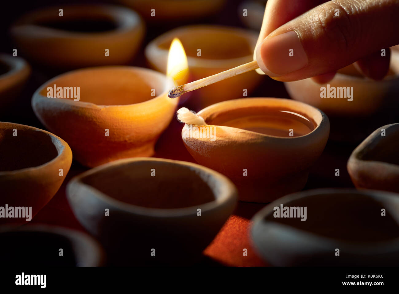 Hand mit einem Streichholz Beleuchtung diya Lampen während Diwali Feier Stockfoto