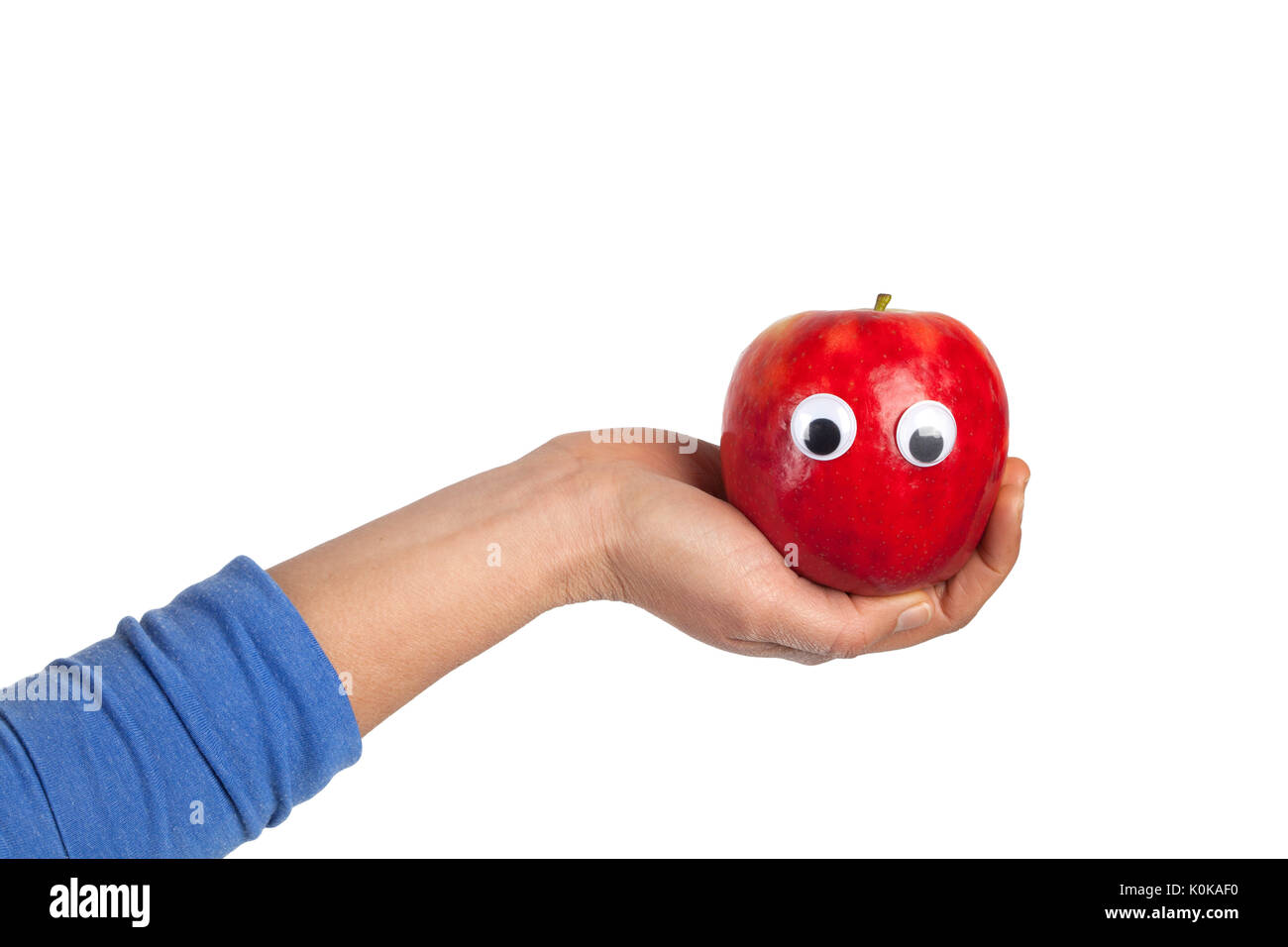 Weibliche Hand hält roten Apfel mit kulleraugen auf weißem Hintergrund mit Kopie Raum isoliert. Gesundes Essen und Lifestyle Konzept Stockfoto