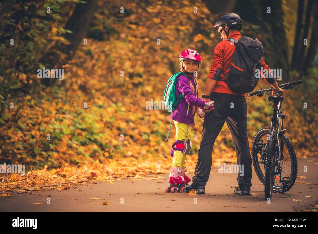 Familie Outdoor Aktivitäten. Vater und Tochter im Park. Radfahren und Rollschuhe. Stockfoto