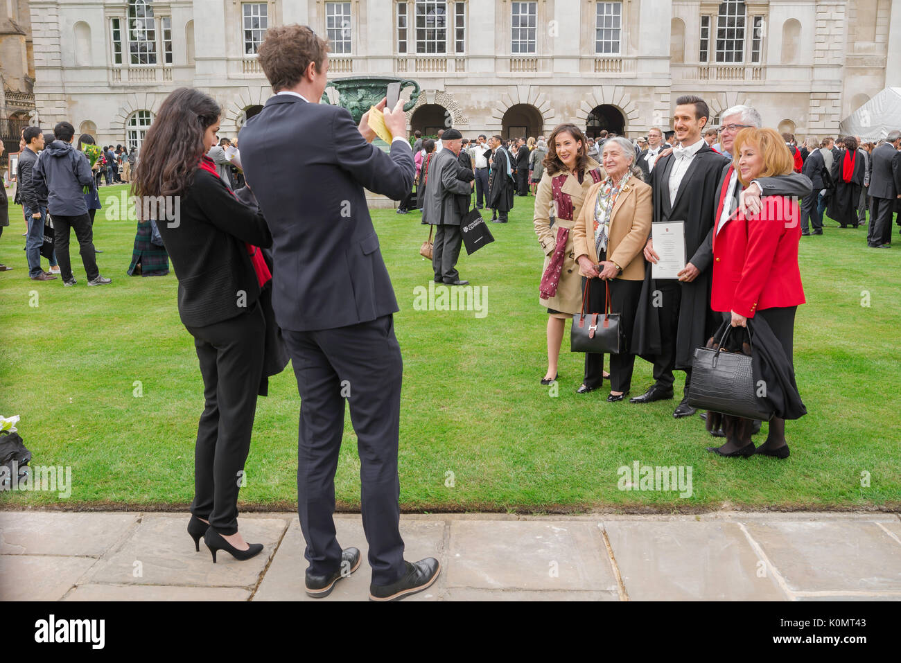 Cambridge Studenten Abschluss, ein frisch graduierte Studenten wirft mit seiner Familie für ein Foto bei der jährlichen Abschlussfeier der Universität Cambridge, Großbritannien. Stockfoto