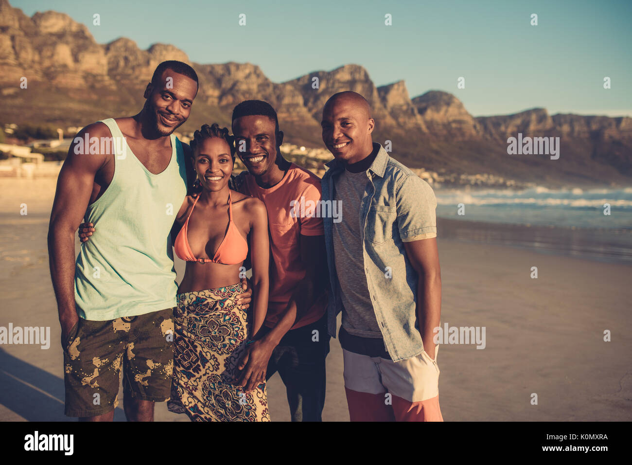 Gruppe von vier Freunde an der Kamera schauen und lächeln. Junge Leute zusammen am Strand. Stockfoto