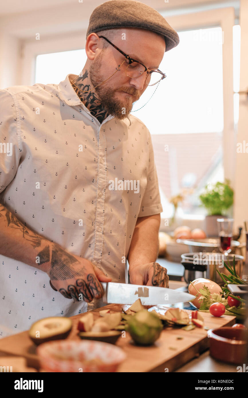 Tätowierten mann Zubereitung von Speisen in der Küche Stockfoto