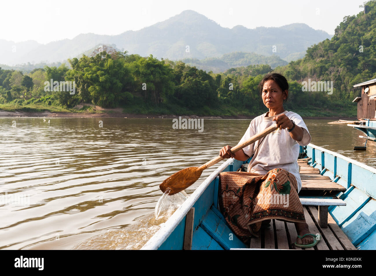 Eine Frau navigiert ein langboot auf Mekong River in der Nähe von Pak Ou, Provinz Luang Prabang, Laos. Stockfoto