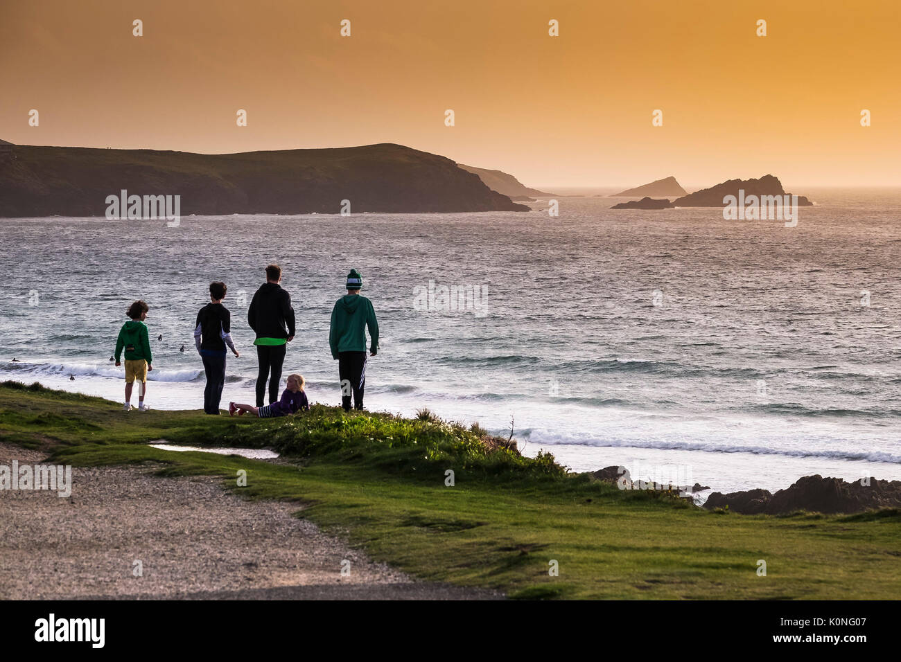 Eine Gruppe von Kindern und Jugendlichen auf Felsen mit Blick auf das Meer an der Nordküste von Cornwall. Stockfoto