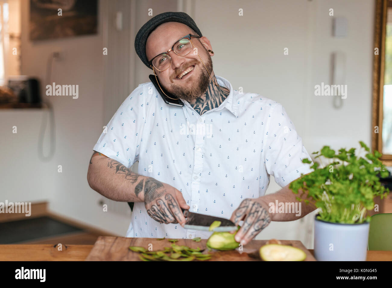 Lächelnd Mann am Telefon Zerkleinern von Gemüse in der Küche Stockfoto