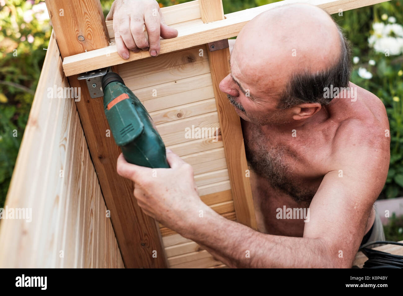 Reifer Mann mit Bohrmaschine Gebäude etwas an contryhouse Stockfoto