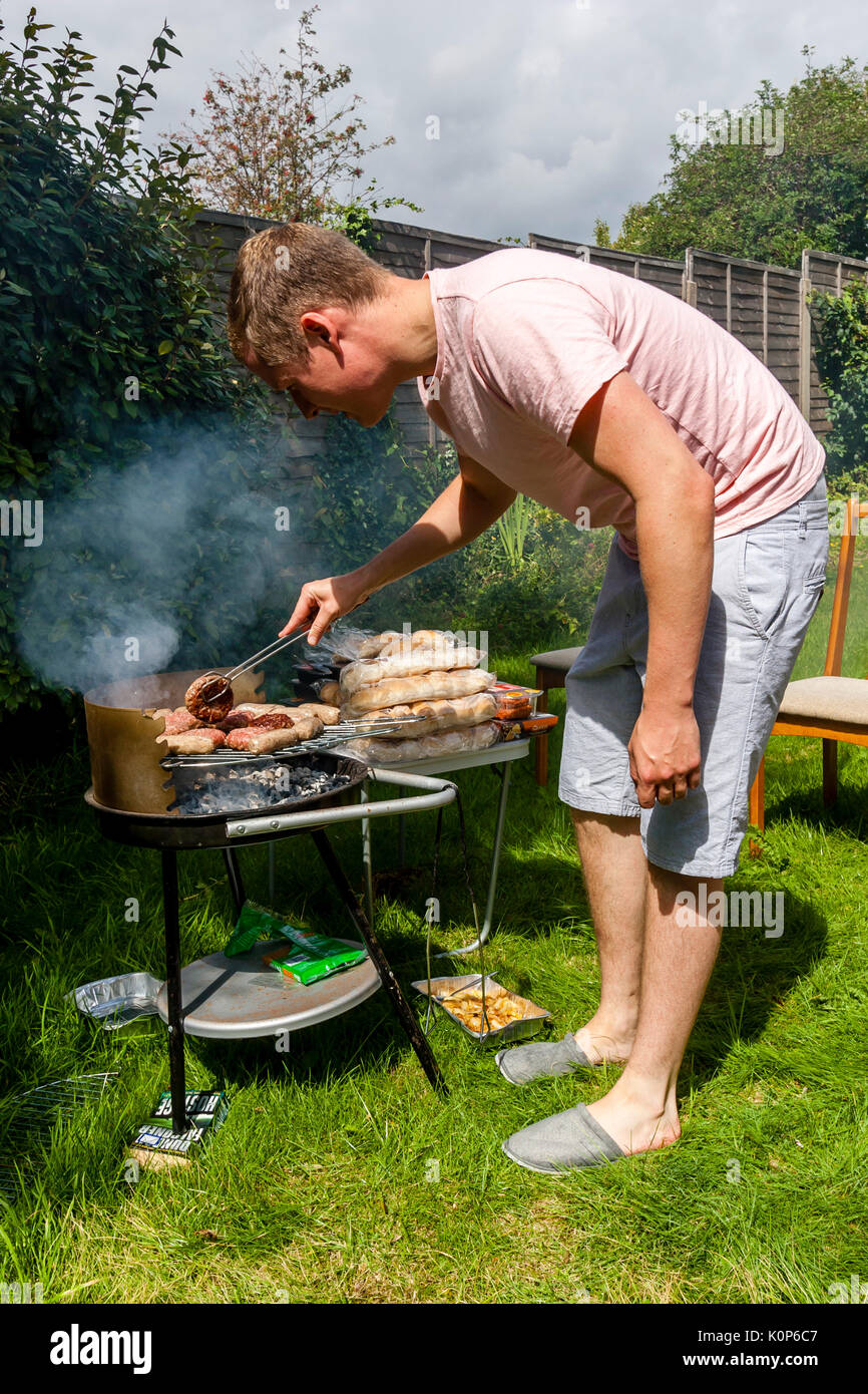 Ein junger Mann Kochen auf einem Grill, Sussex, UK Stockfoto