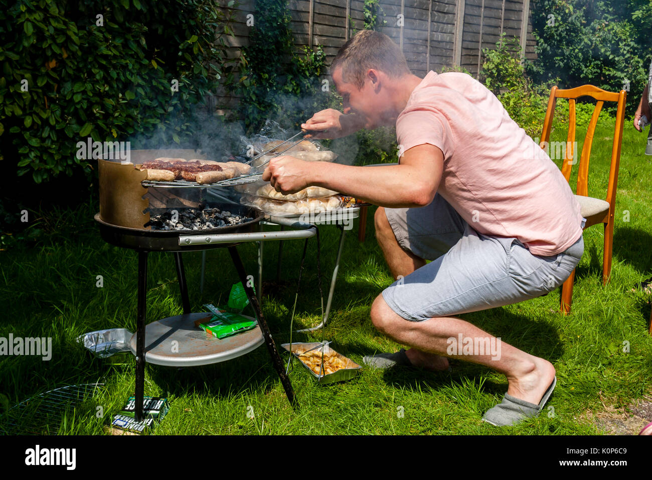 Ein junger Mann Kochen auf einem Grill, Sussex, UK Stockfoto