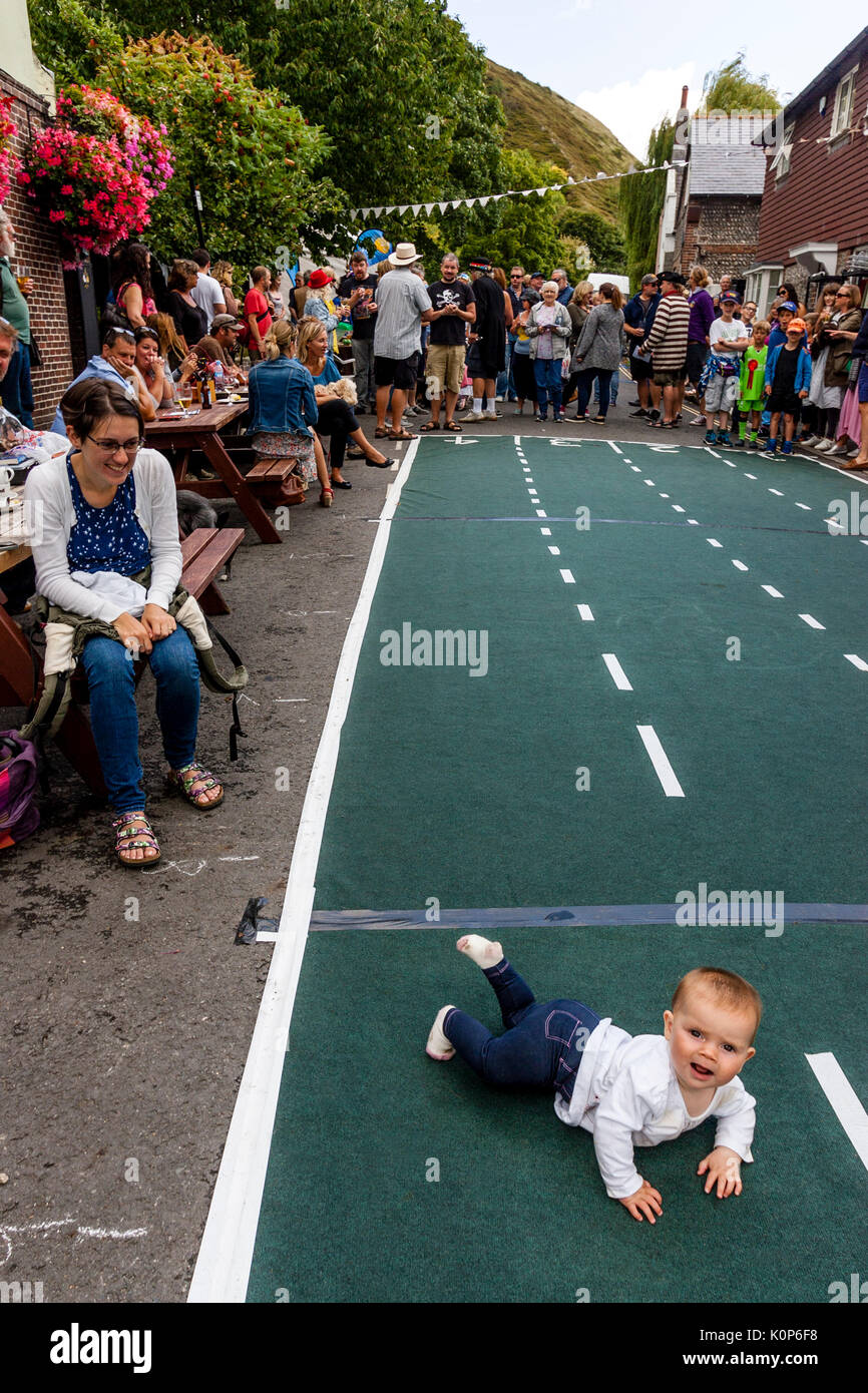 Ein Baby Krabbelt über die vorübergehende Rennen Tack Am jährlichen South Street Sport Tag und Hund zeigen, Lewes, East Sussex, Großbritannien Stockfoto