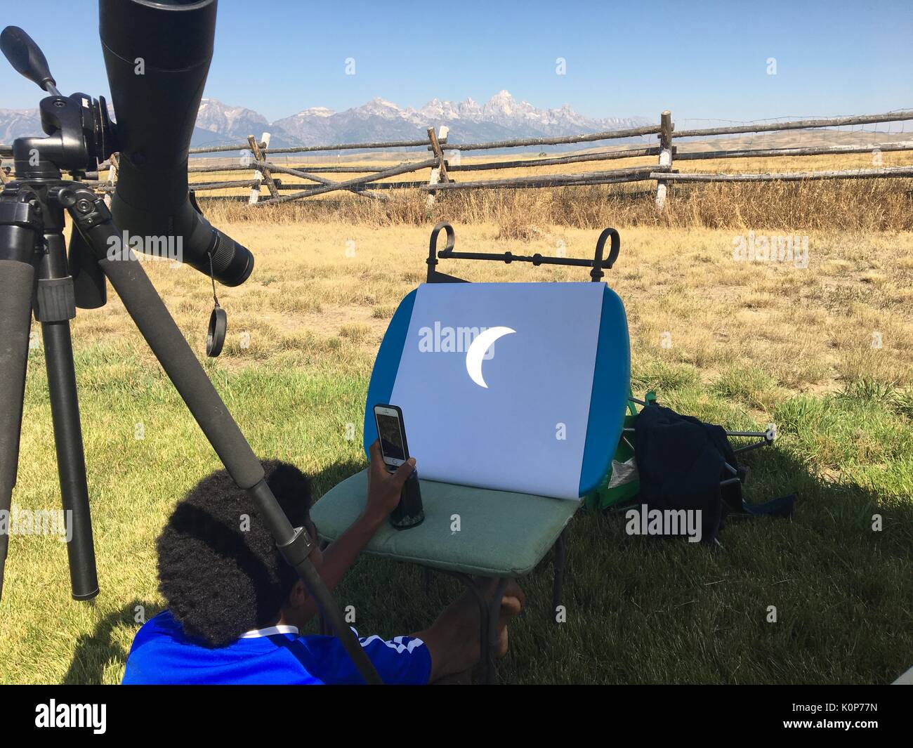 Ein kleiner Junge nimmt ein Foto einer Projektion der Sonnenfinsternis mit einem Spektiv das Bild der Sonne auf ein Stück Papier an der National Elk Refuge 21. August zum Projekt erstellt, 2017 in Jackson, Wyoming. Die totale Sonnenfinsternis über einem schmalen Teil des angrenzenden Vereinigten Staaten von Oregon nach South Carolina und eine partielle Sonnenfinsternis war über den gesamten nordamerikanischen Kontinent sichtbar zusammen mit Teilen von Südamerika, Afrika und Europa. Stockfoto