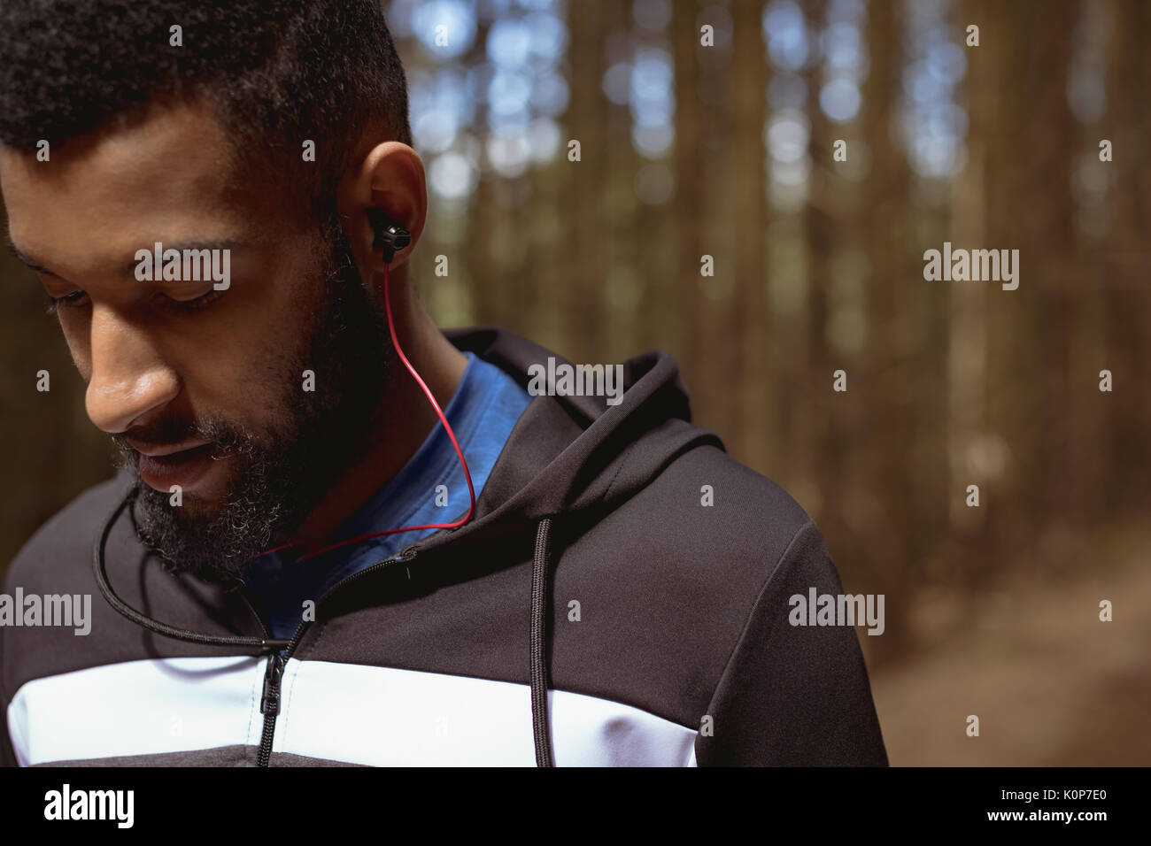 Der junge Mann Musik hören beim Stehen in Wald Stockfoto