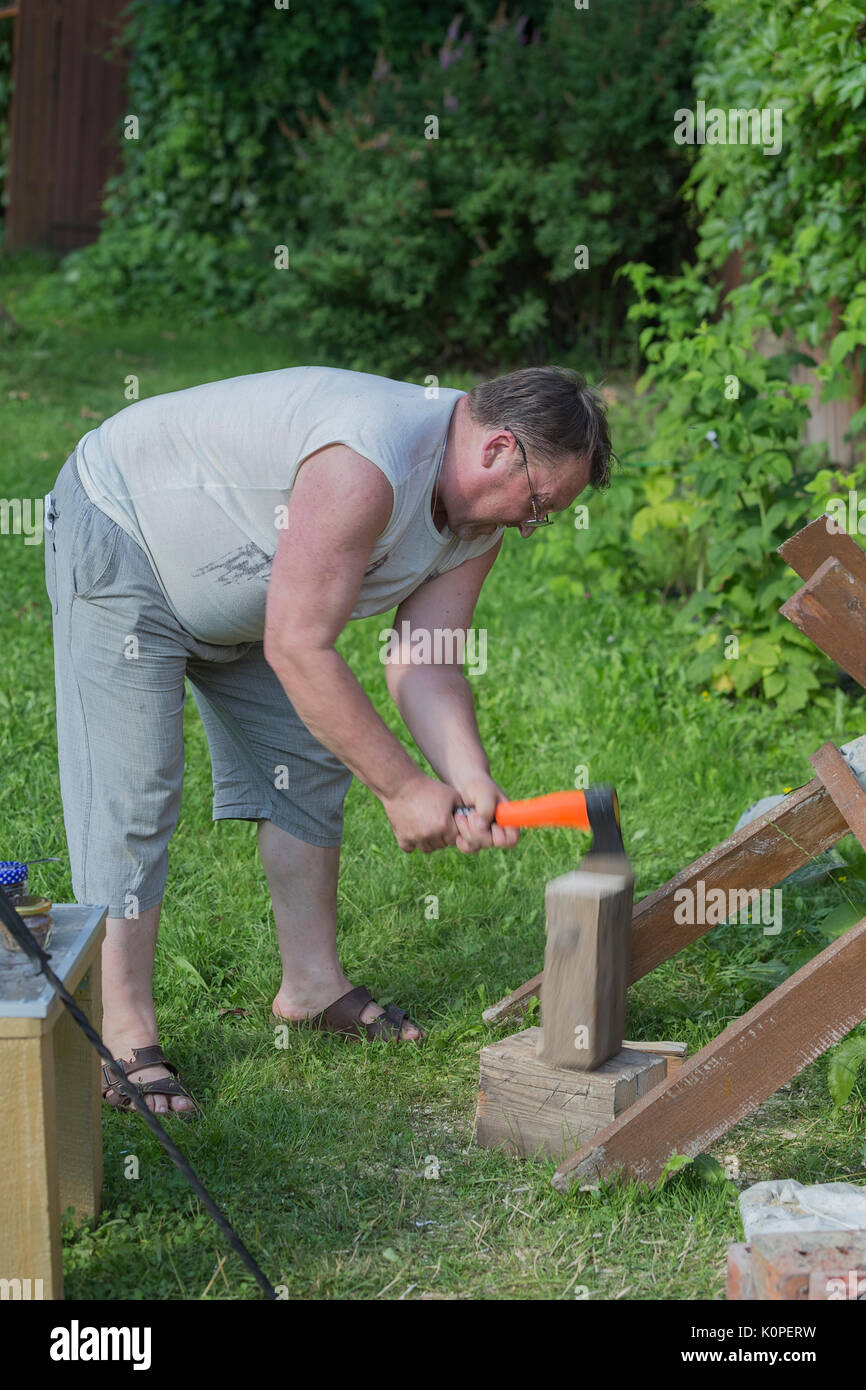 Junger Mann schneidet Holz mit einer Axt Stockfoto