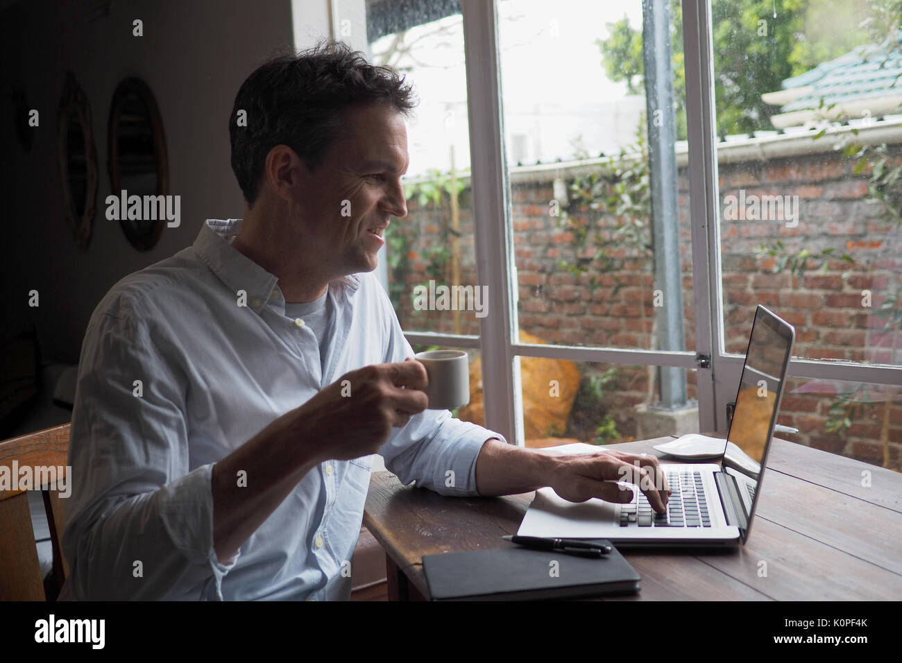 Man trinkt Kaffee am Computer in home office Stockfoto