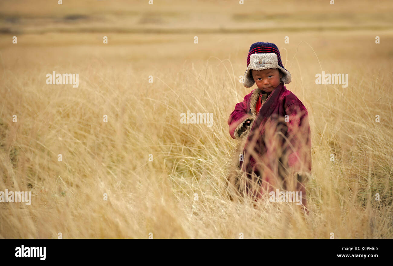 Tibetische Kid spielen rund um die Weideplätze der tibetischen Hochebene während der letzten Ernte Tage vor der ersten Schneestürme beginnen Stockfoto