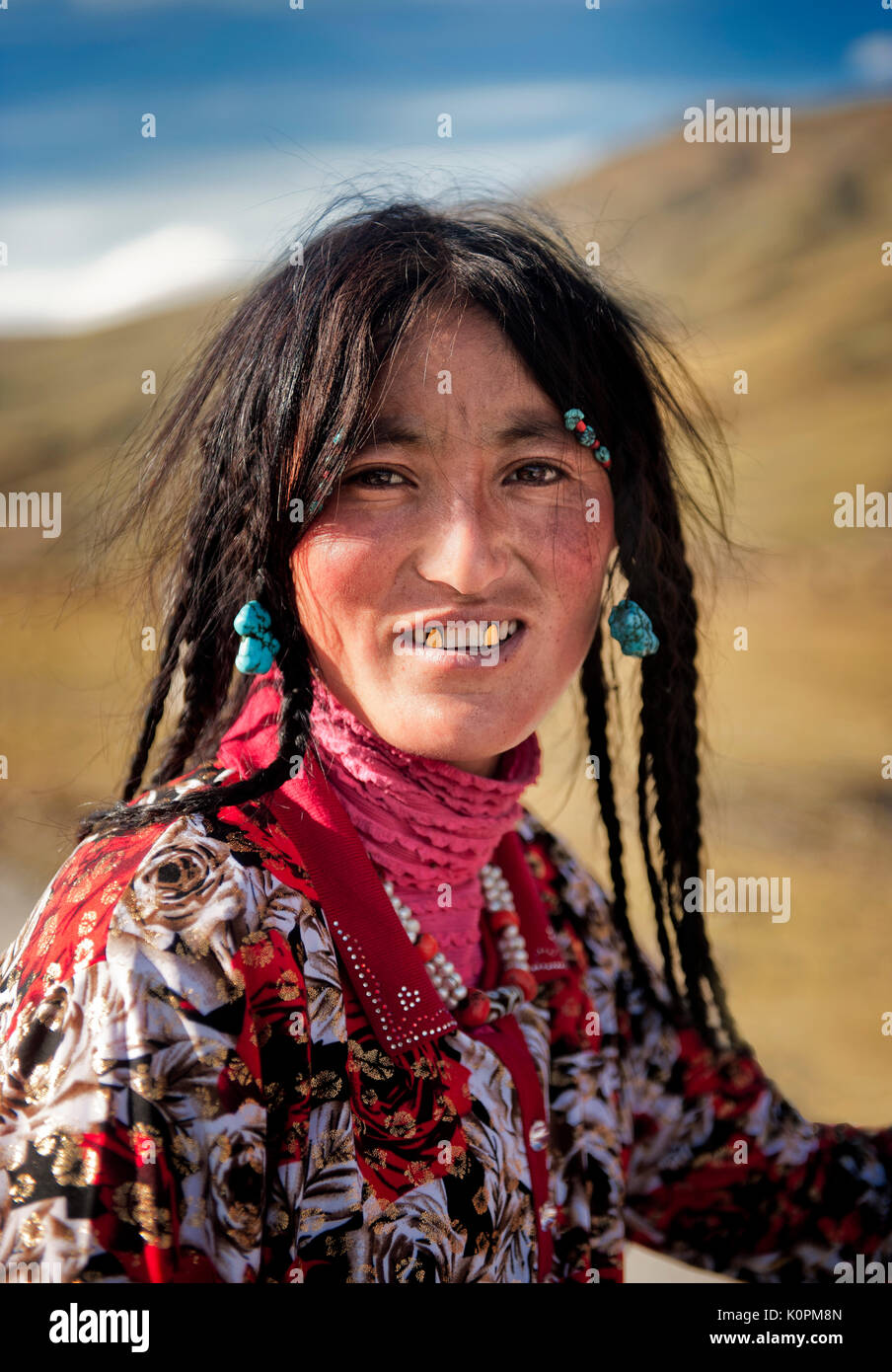 Ein tibetischer Junge Frau das Tragen der traditionellen Zubehör typisch für ihre ethnische Gruppe sowie ihre Fangzähne in Gold bedeckt, Remote tibetischen Plateau Stockfoto