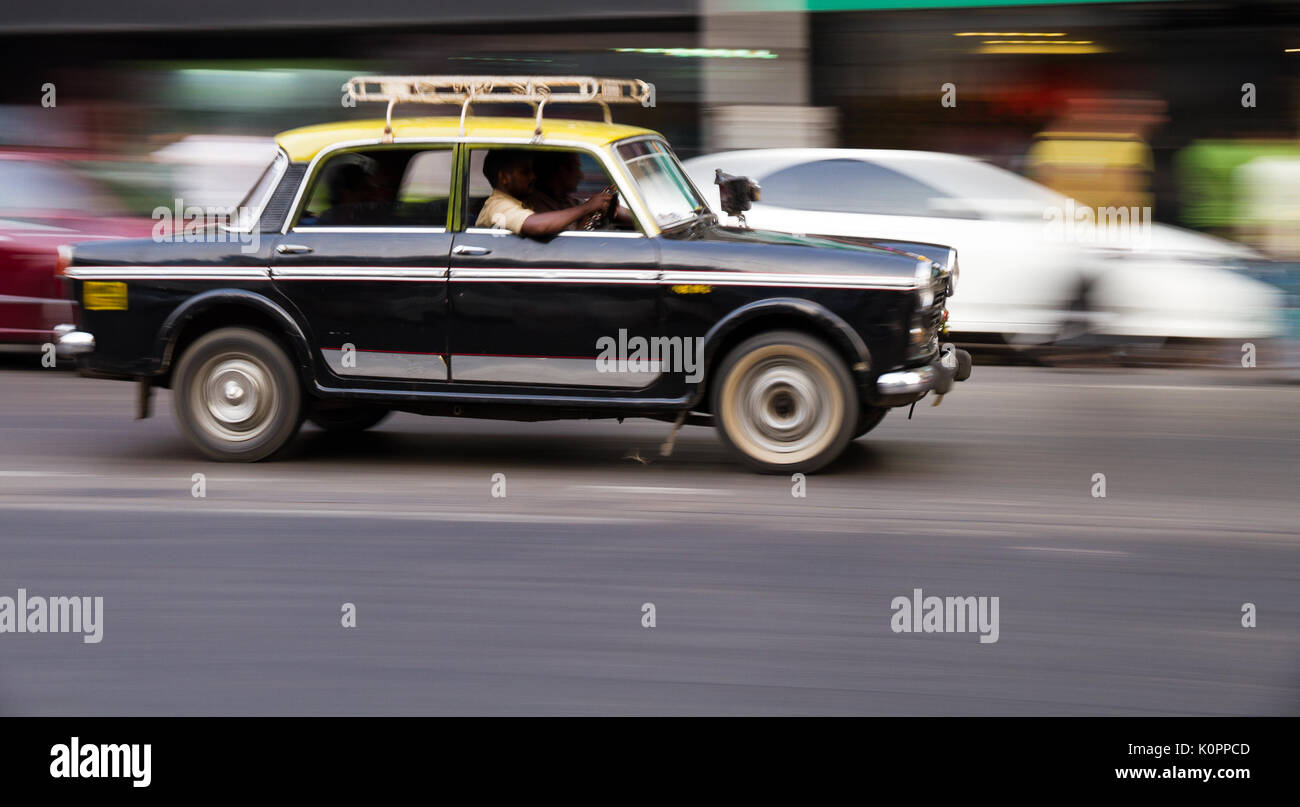 Alte traditionelle schwarze und gelbe Taxi in Bewegungen mit Motion Blur (Panning) in den Straßen von Mumbai, Indien dargestellt Stockfoto