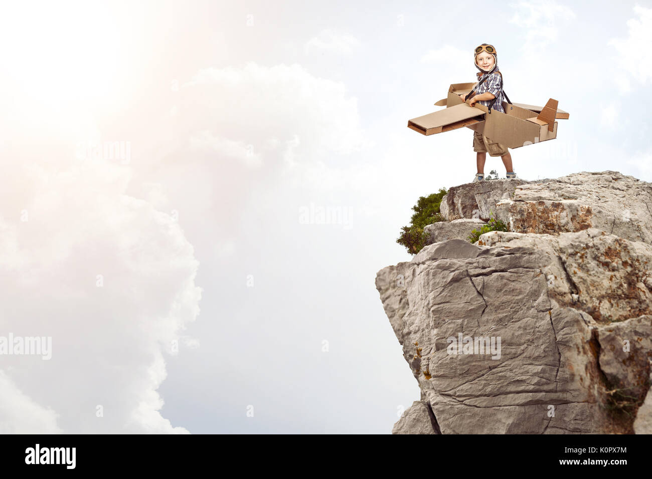 Portrait der kaukasischen Kind spielen mit Karton Flugzeug auf einer Klippe Stockfoto