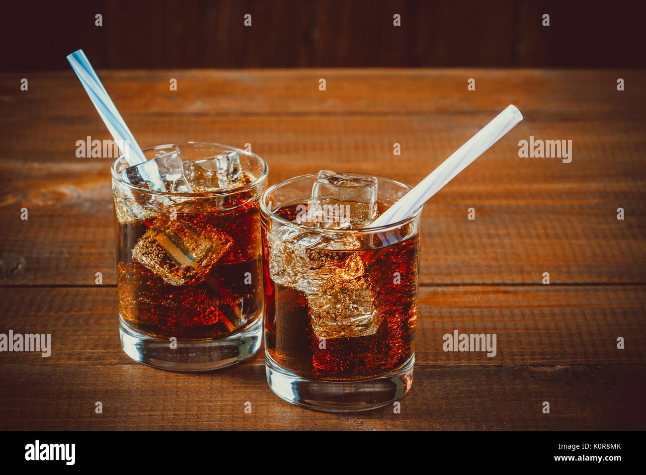 Schöne kalte Getränke von Cola mit Eiswürfeln mit einem Kessel Strohhalme in Gläsern auf hölzernen Hintergrund mit freier Speicherplatz Stockfoto