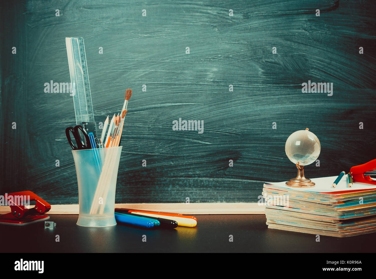 Alte Tafel mit Kreide, Bücher, eine Kugel und einen Bleistift. Einen schönen Hintergrund für Bildung, einen freien Platz für Ihren Text. Zurück zu Schule. Flache Freiheitsgrad. Stockfoto