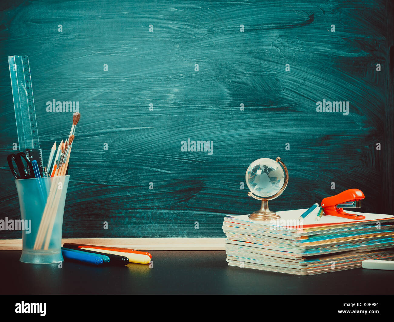 Alte Tafel mit Kreide, Bücher, eine Kugel und einen Bleistift. Einen schönen Hintergrund für Bildung, einen freien Platz für Ihren Text. Zurück zu Schule. Flache Freiheitsgrad. Stockfoto