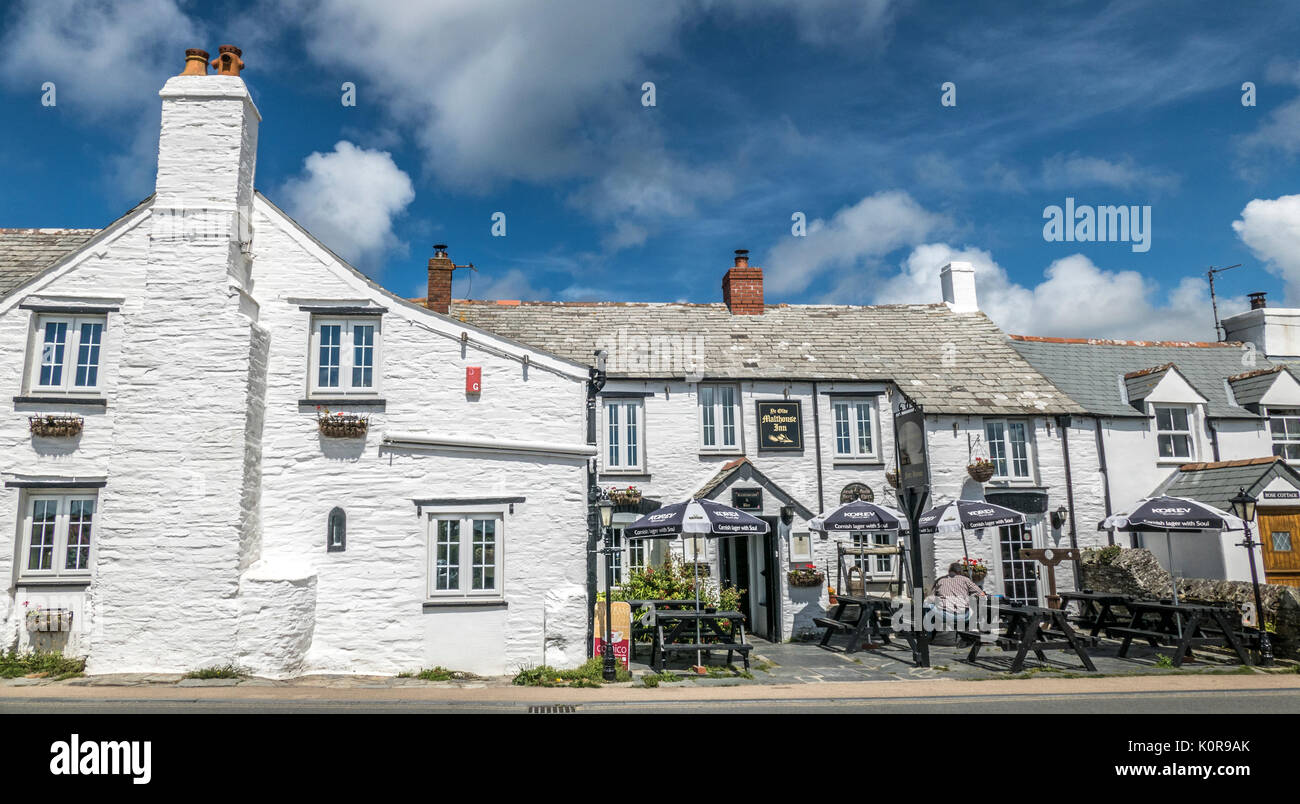 Mann außerhalb Mälzerei Inn, Fore Street, Tintagel, Cornwall, England, Großbritannien sitzen. Eine Taverne aus dem 14. Jahrhundert, heute ein Restaurant mit regionalen Ales. Stockfoto