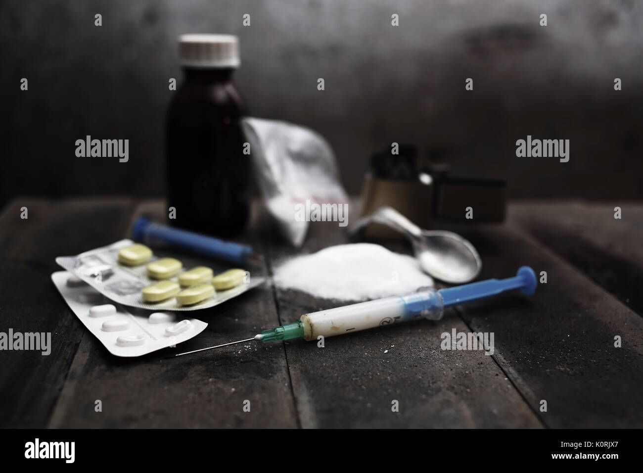 Harte Drogen auf dunklen Tisch. Ein dunkles Thema, den Drogenkonsum. Vorbereitung von Drogen, noch Leben. Spritze mit Kanüle, Löffel, Tabletten, leichter. Der Tod. Stockfoto