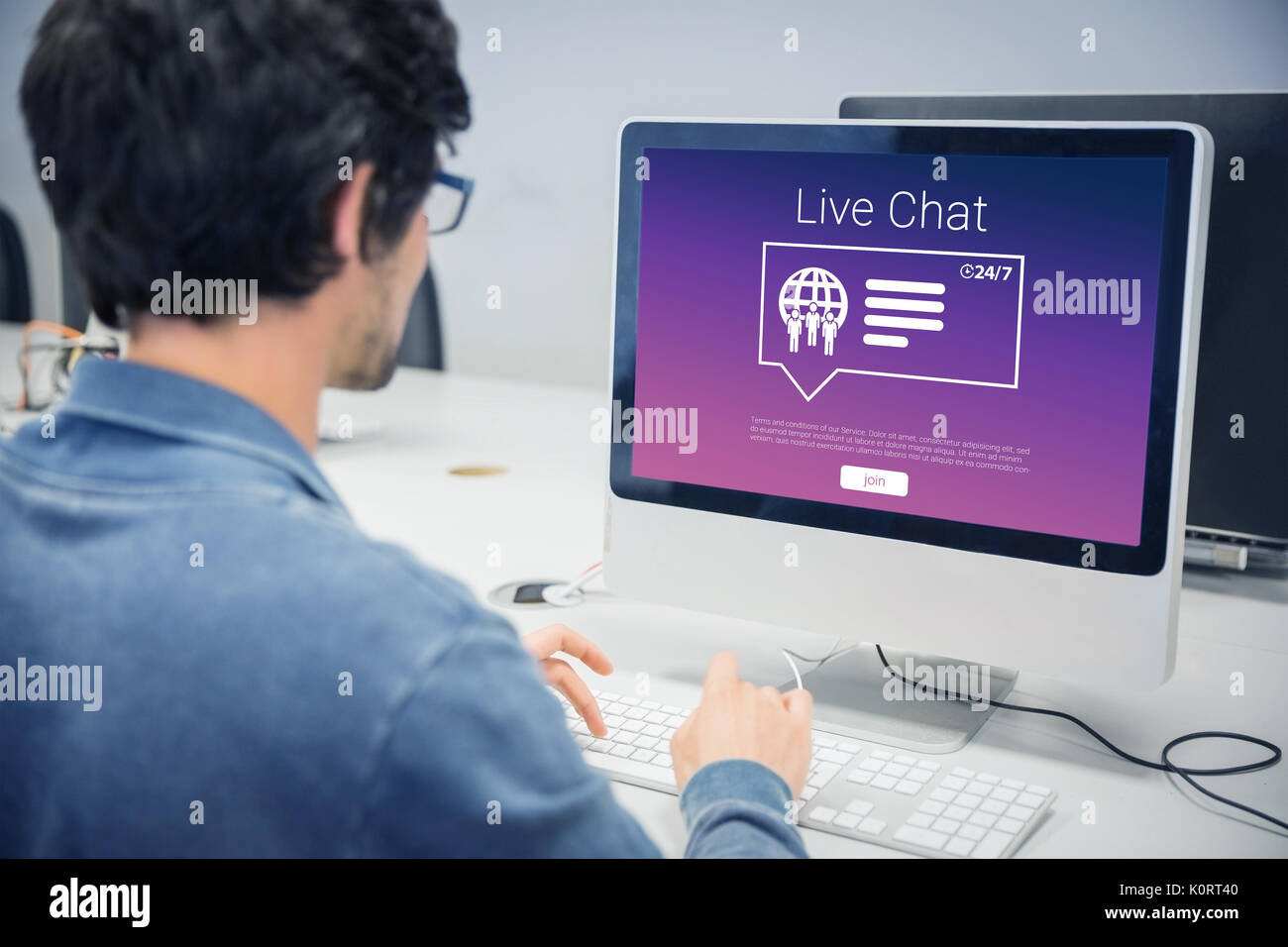 Symbole mit Live chat Text gegen über der Schulter auf der ernsten legerer Mann am Computer Schreibtisch arbeiten Stockfoto