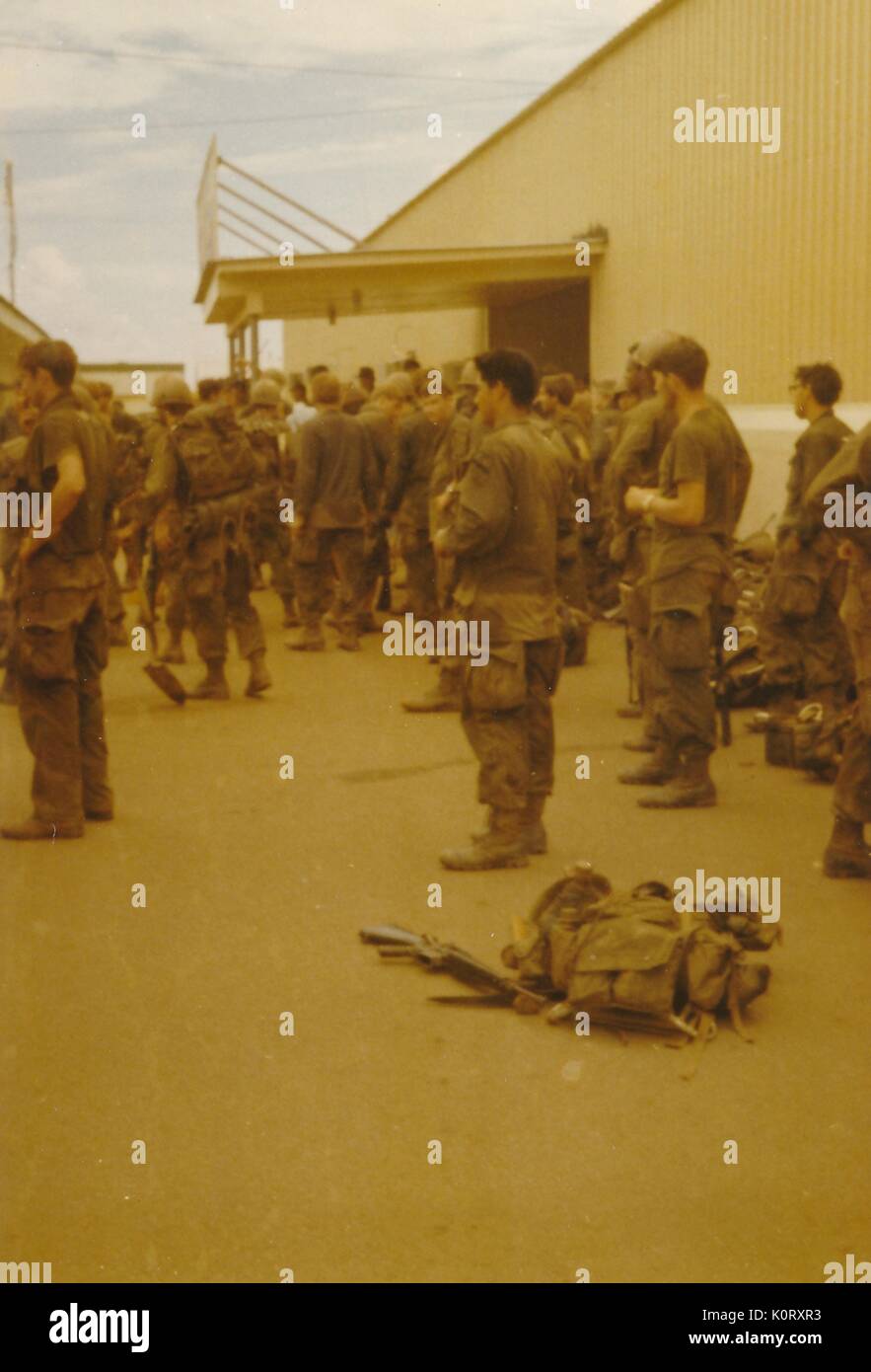 Eine große Gruppe von Soldaten in ihren Uniformen gesammelt wurden, zeigen alle in dieselbe Richtung, deren Bekämpfung Gangs gegen ein Gebäude, Vietnam, 1964 an die Seite gestellt wurde. Stockfoto