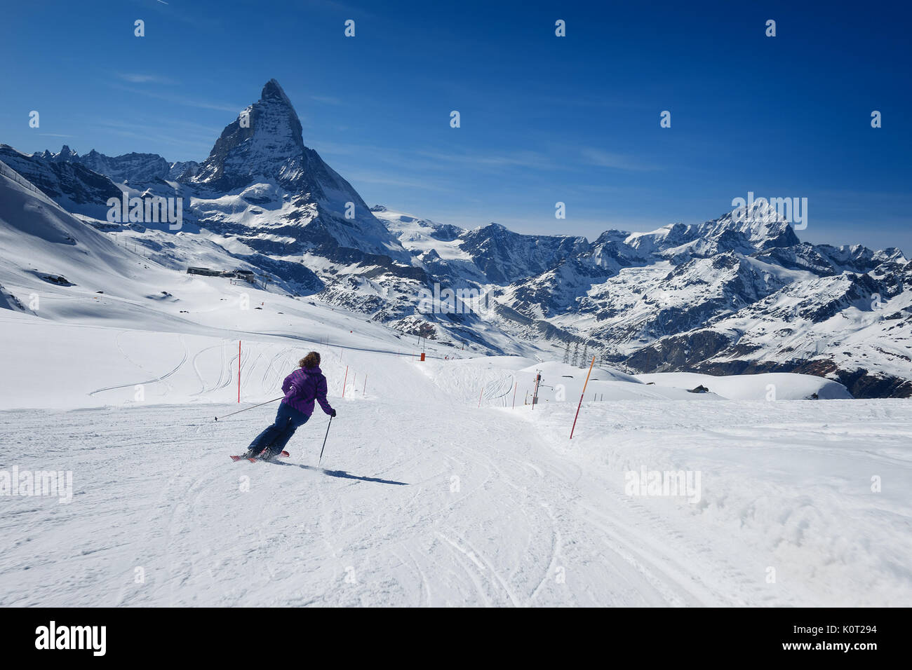 Skifahrerin Skifahren allein auf der Piste in Richtung Matterhorn an einem sonnigen Tag im Skigebiet Zermatt im Kanton Wallis in der Schweiz. Stockfoto