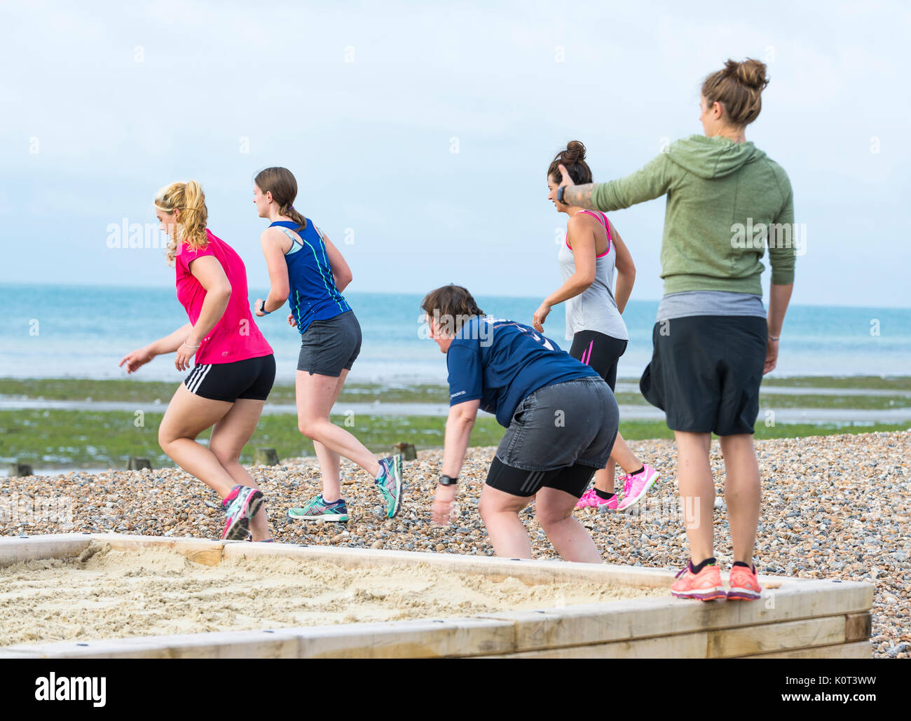 Übung Klasse am Strand. Kleine Gruppe von jungen Frauen in einem fitnesskurs Ausübung auf einem Strand am Morgen in Großbritannien. Stockfoto