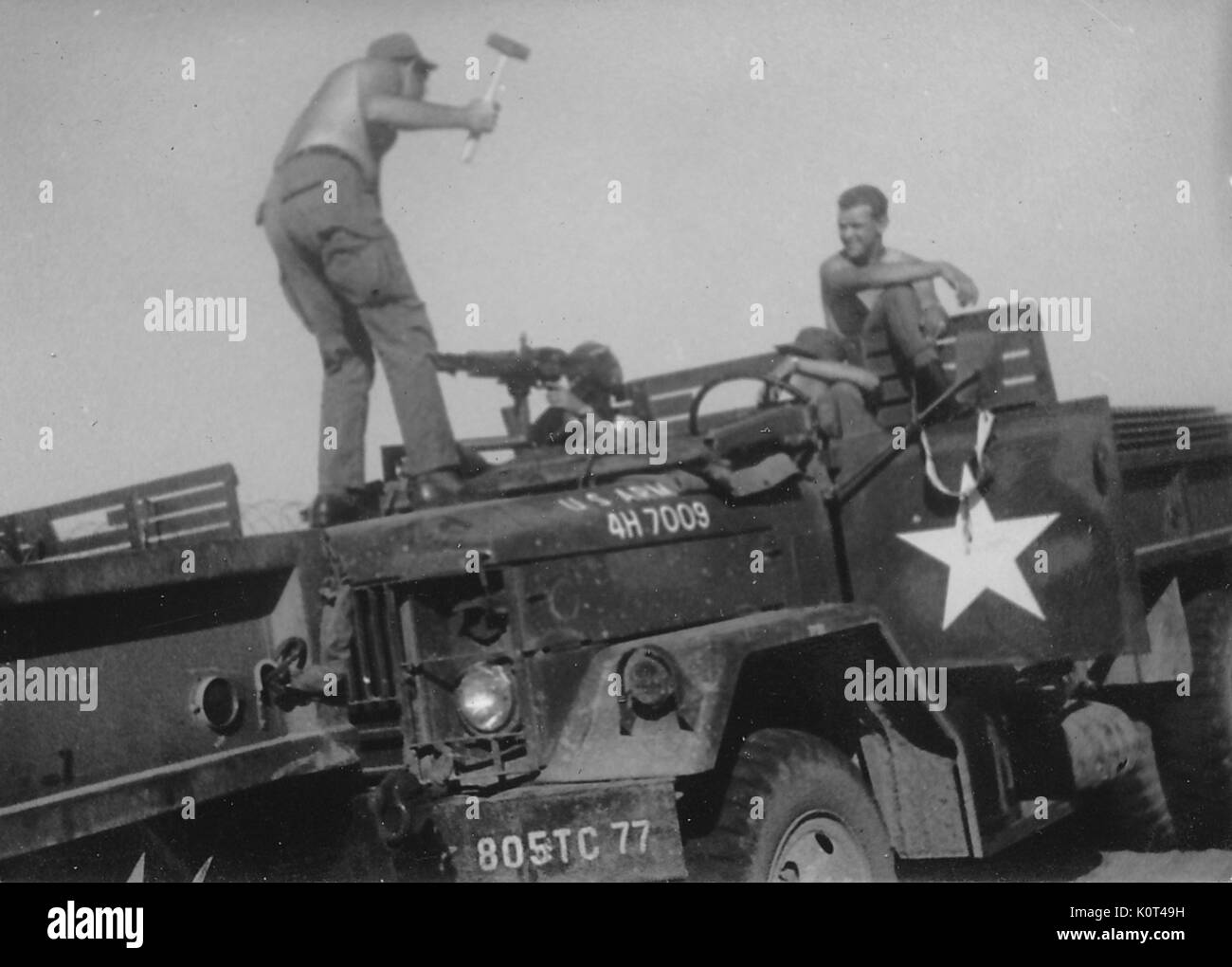 Ein Foto von vier United States Army Veteran amüsant Auf einen geparkten M 35 Militär-LKW, zwei der Soldaten in Unterhaltung ansehen, während ein Soldat mit einem Hammer auf die Motorhaube des Fahrzeugs vor ein anderer Soldat, der einen Hand auf einen montierten M60 Maschinengewehr, Vietnam, 1967 steht. Stockfoto