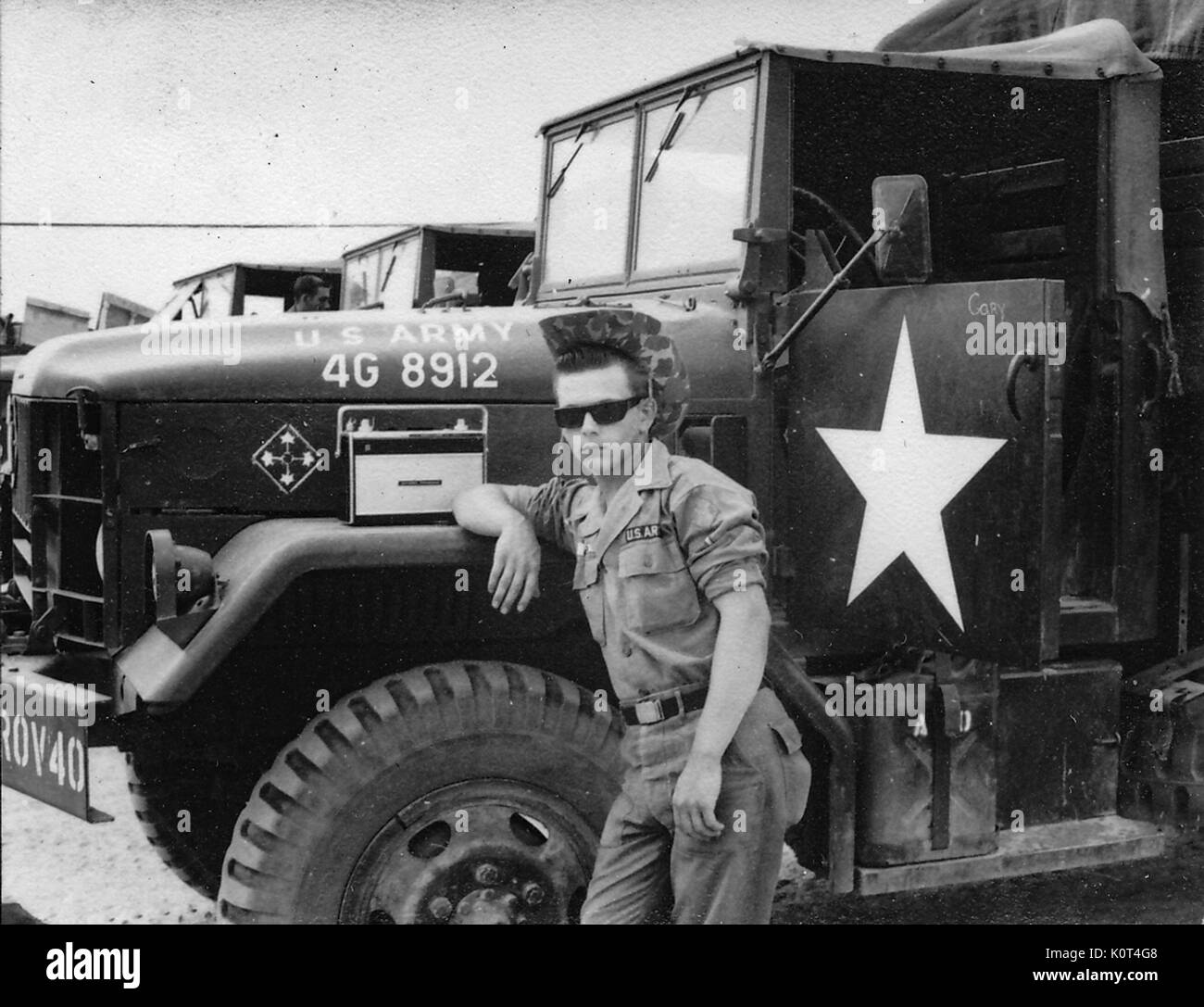 Ein United States Army Veteran das Tragen einer Uniform, ERDL boonie tropischen Hut und Sonnenbrille, er lehnt sich ein Kniestück auf dem Kotflügel eines M 35 Militär-LKW, Vietnam, 1967. Stockfoto
