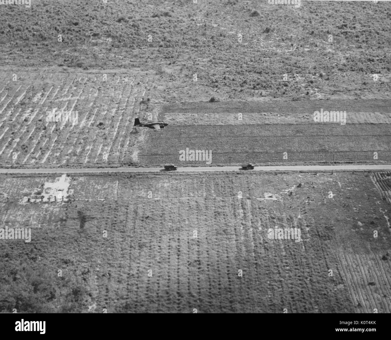 Ein Foto von einem Flugzeug, die Abdeckung für ein kleiner LKW Konvoi entlang einer Straße zwischen Feldern, Vietnam, 1967 gelegen. Stockfoto