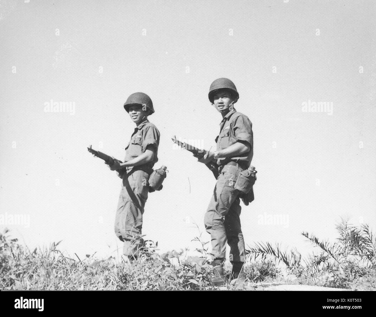 Ein Foto von zwei Soldaten der Armee der Republik Vietnam, die aufgeworfen werden auf einem Hügel, während ihre Bekämpfung Gewehre auf Taillenhöhe, Vietnam, 1968. Stockfoto