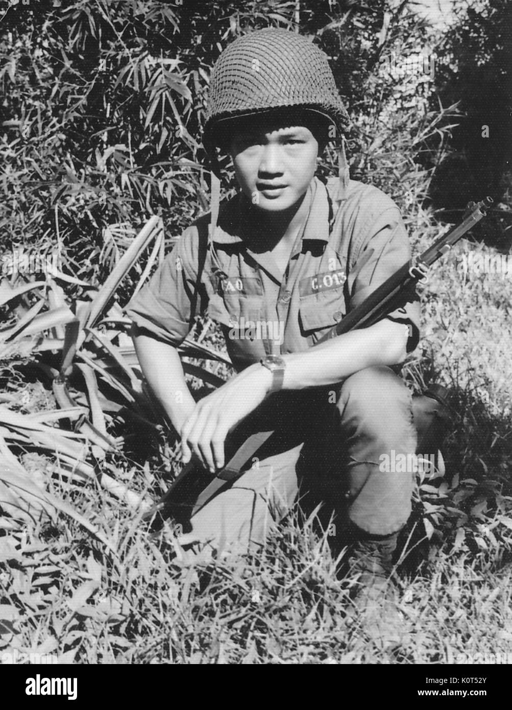 Ein Foto einer Armee der Republik Vietnam Soldat mit seinem Gewehr Position in seinem Schoß, Vietnam, 1968 kauerte. Stockfoto