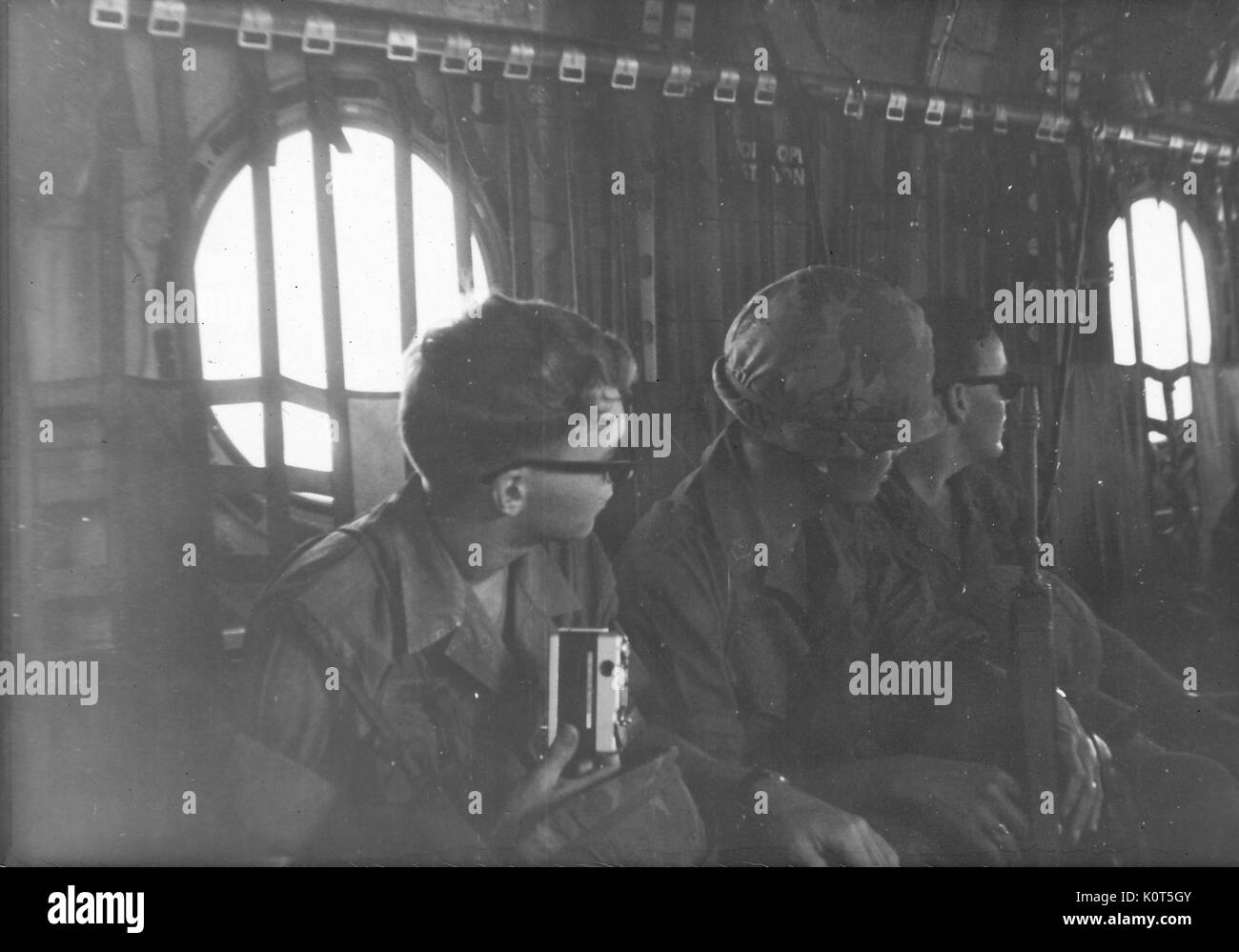 Eine Reihe von drei United States Army Soldaten in das Innere der Flugzeuge, ein Soldat hält eine persönliche Kamera, während ein anderes seine Kampf Gewehr hält, Vietnam, 1967. Stockfoto