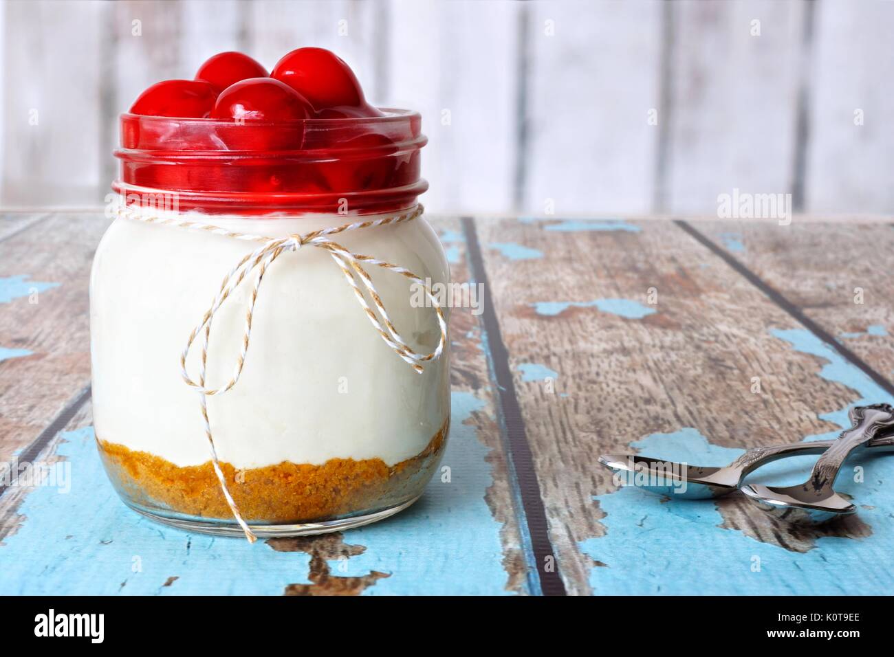 Sweet Cherry Cheesecake in einem Marmeladenglas auf einem rustikalen, mit Holz Hintergrund Stockfoto