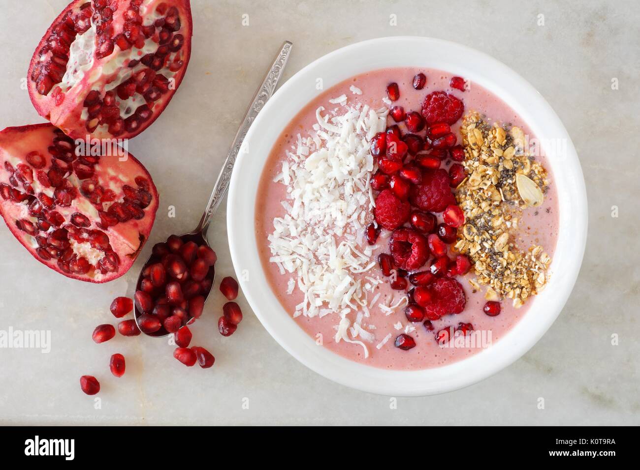 Smoothie Schüssel mit Granatäpfel, Himbeeren, Kokos und Müsli, Overhead Szene auf Marmor Stockfoto