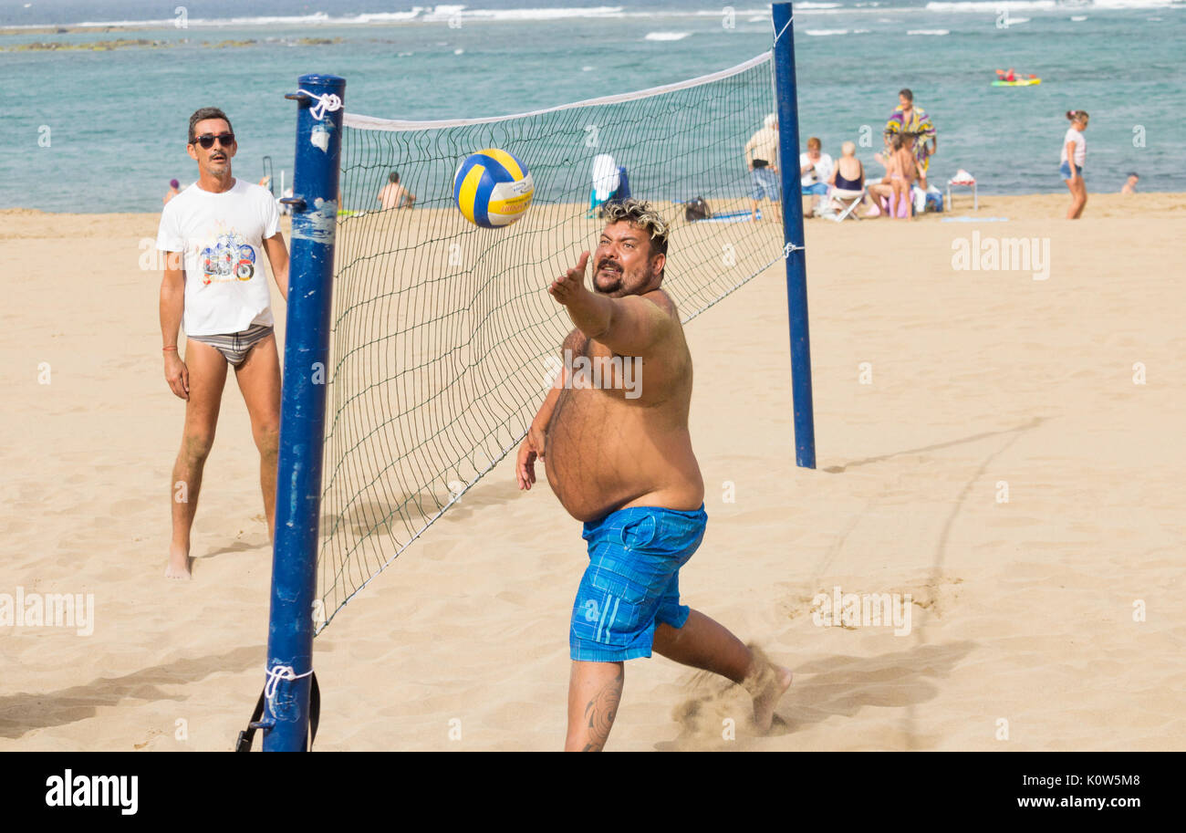 Übergewichtige Menschen spielen Volleyball am Strand in Spanien Stockfoto